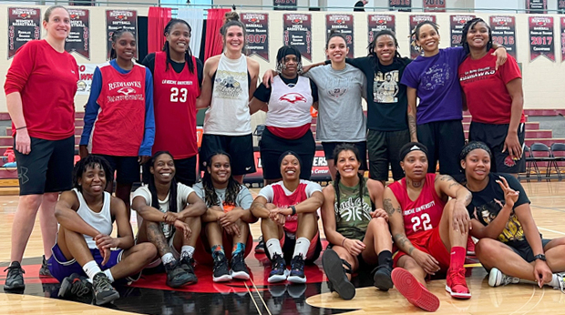 A group of La Roche University women's basketball alumni poses for a photograph on court in the Kerr Fitness & Sports Center.