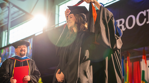 A La Roche University graduate earning a master's degree receives a sash on stage at commencement. 