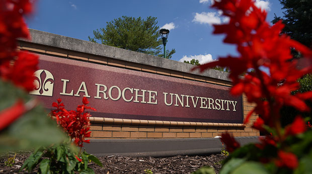 The La Roche University entrance sign surrounded by red flowers.