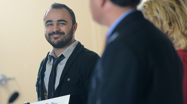 A La Roche University student in a suit and tie smiles at another person.