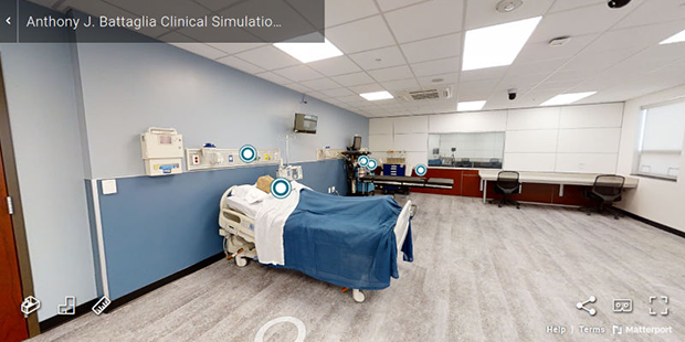 A view of the Anthony J. Battaglia Clinical Simulation Center. The room shows a hospital bed with a mannequin, medical equipment and a work station with two chairs. A view of the Anthony J. Battaglia Clinical Simulation Center. The room shows a hospital bed with a mannequin, medical equipment and a work station with two chairs.