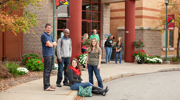 A group of La Roche University students hang out in front of the Kerr Fitness & Sports Center building.