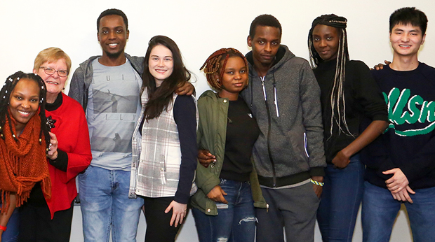 Group of eight La Roche University students smiling in a classroom setting.
