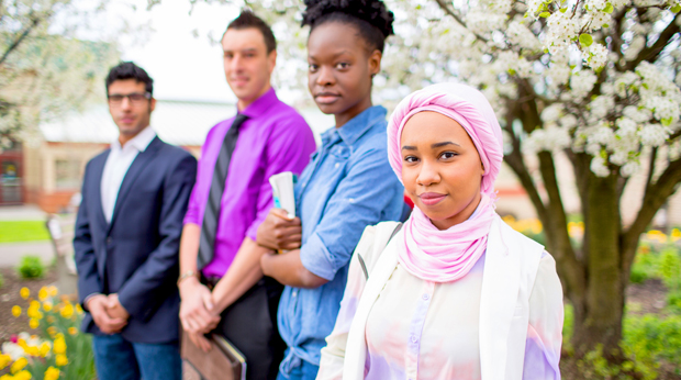 Four La Roche University students stand in front of a blooming tree outside of the Wright Library.