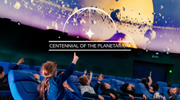 A group of school children looking up and pointing to the displays in a planetarium dome.