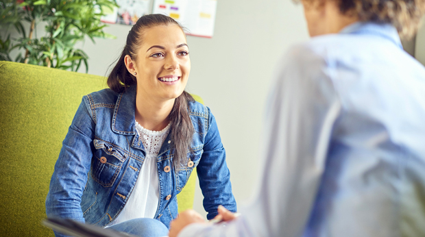 A client and a therapist talk to each other in an office setting.