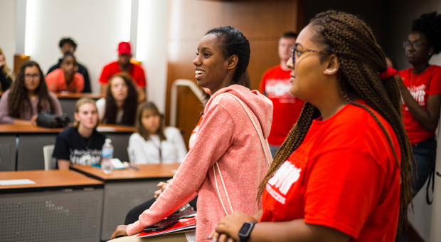 Two La Roche University students present in front of a class in an auditorium classroom.